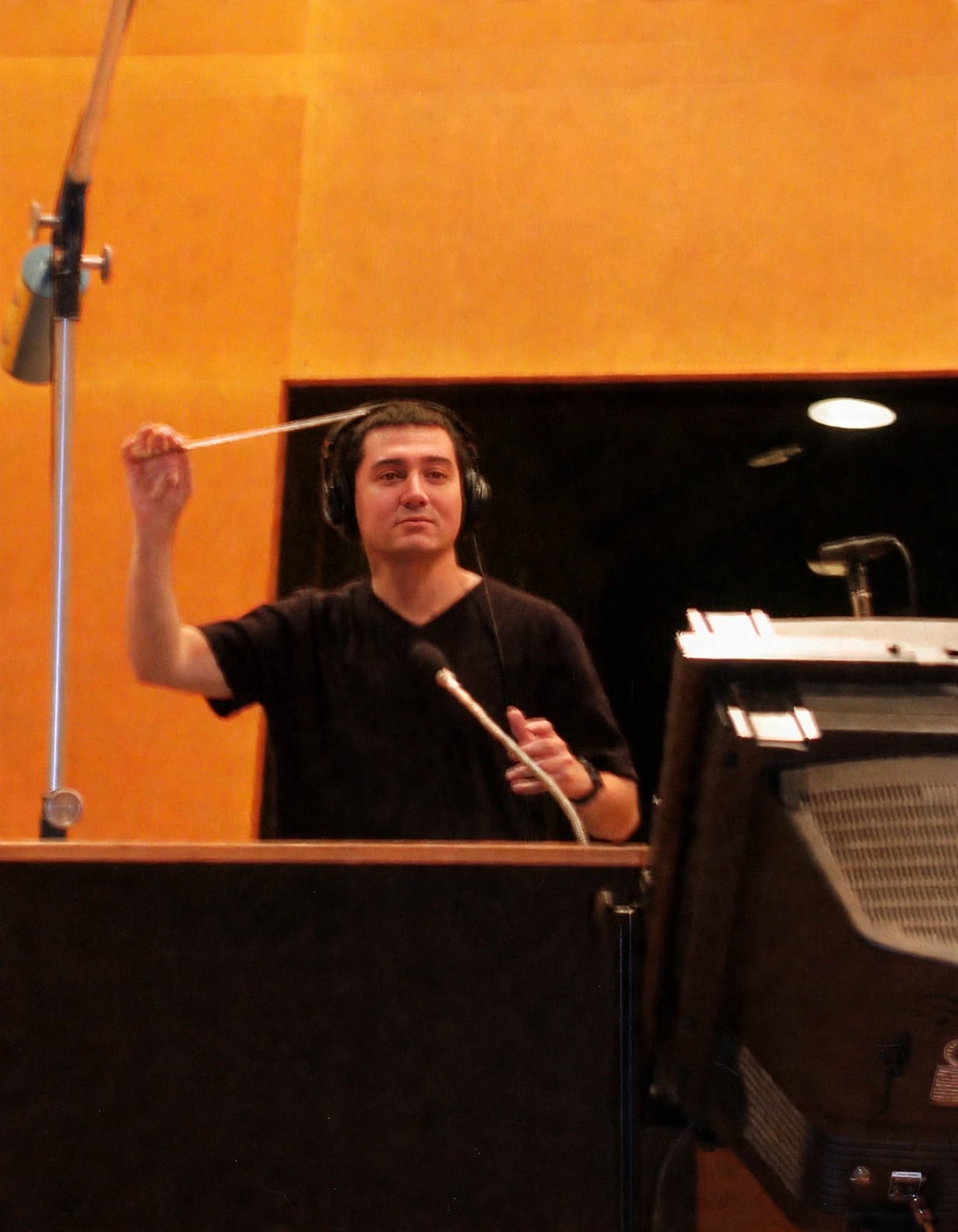 Jason Solowsky conducting with headphones on, baton raised